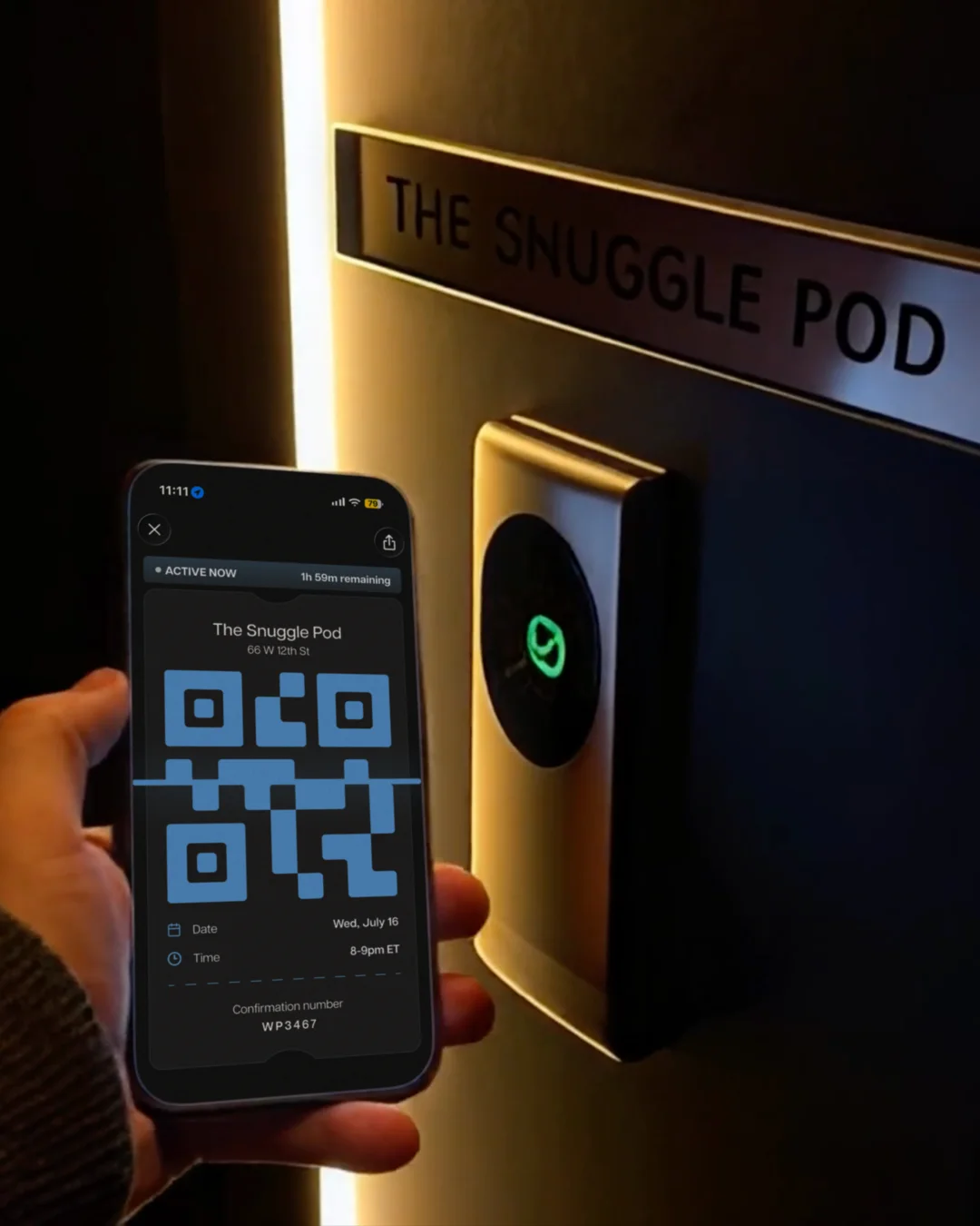 A phone showing the active QR ticket, held up to the door of The Snuggle Pod